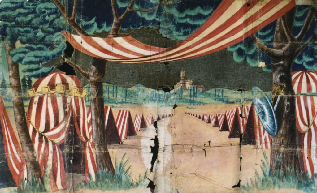 MET – Museo Etnografico degli Usi e Costumi della Gente di Romagna “ACCAMPAMENTO”, fondale per teatro di burattini appartenuto a Francesco Campogalliani (Ferrara, 1870-1931). Cm. 139x222 Fondale costruito in carta per scenografia, telata lungo il perimetro e nelle piegature. Dipinto a tempera. Fu in uso a Francesco Campogalliani tra la fine dell’ottocento e i primi trent’anni del novecento per mettere in scena "Sandrone in viaggio di nozze"